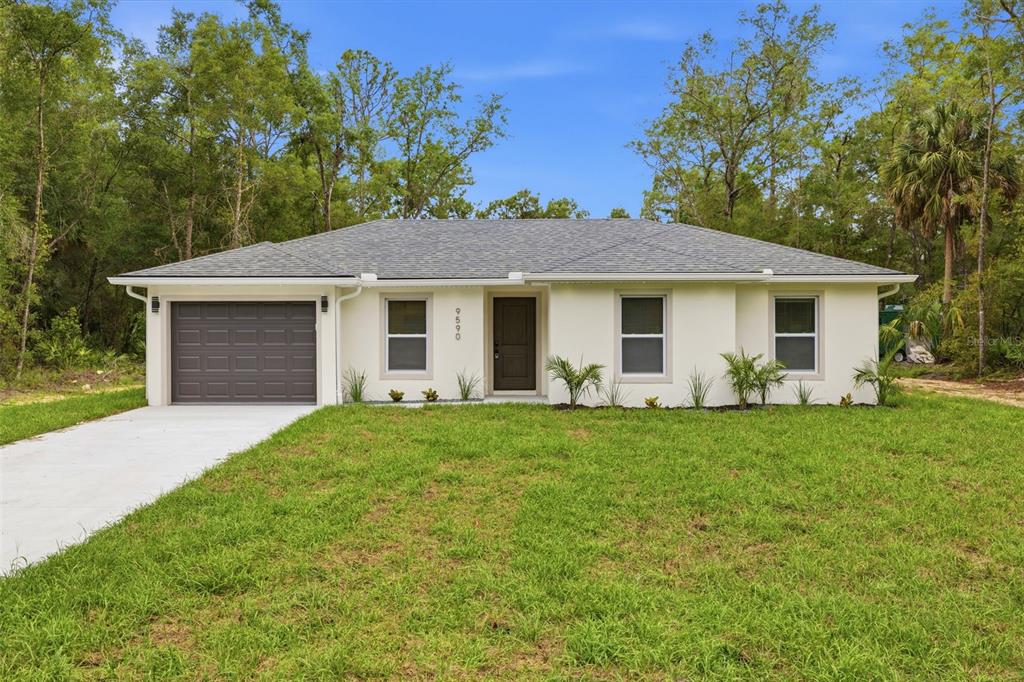 A single-story house with a white exterior, gray roof, and attached garage sits on grass — 9590 W TENNESSEE LANE, CRYSTAL RIVER, FL