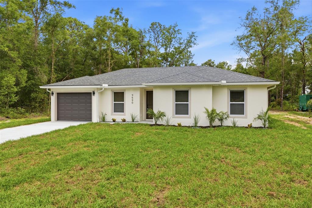 A single-story house with a gray roof, white stucco exterior, and a one-car garage — 9590 W TENNESSEE LANE, CRYSTAL RIVER, FL