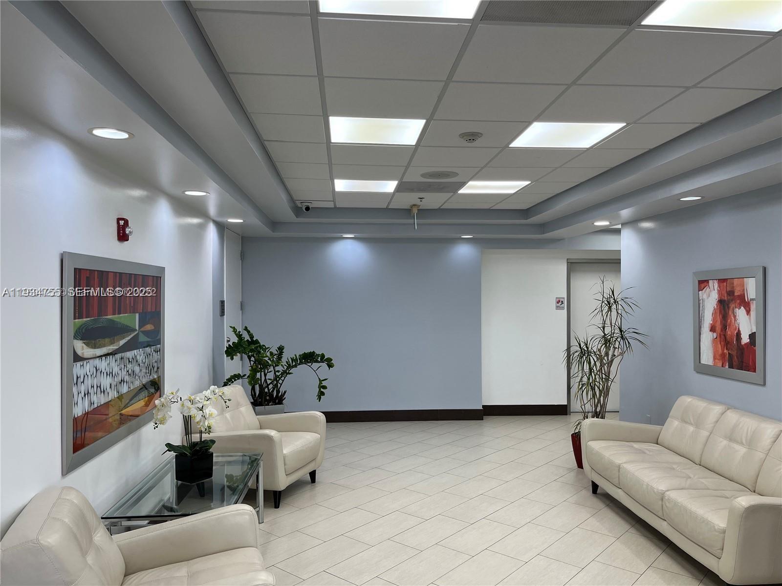 A waiting room features light-colored tile flooring, white leather furniture, and two framed wall paintings — 18191 NW 68th Ave, Miami FL 33015, MIAMI, FL