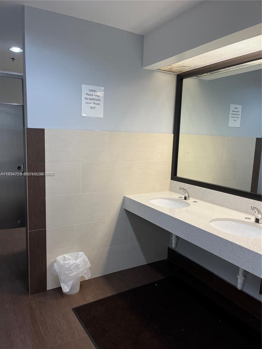 A public restroom features a double vanity with a white countertop and a large mirror — 18191 NW 68th Ave, Miami FL 33015, MIAMI, FL