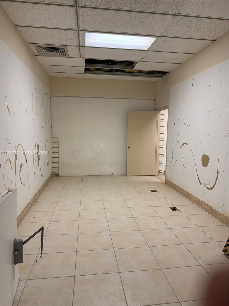 An empty office space features white walls with markings, tiled flooring, and a drop ceiling — 18191 NW 68th Ave, Miami FL 33015, MIAMI, FL