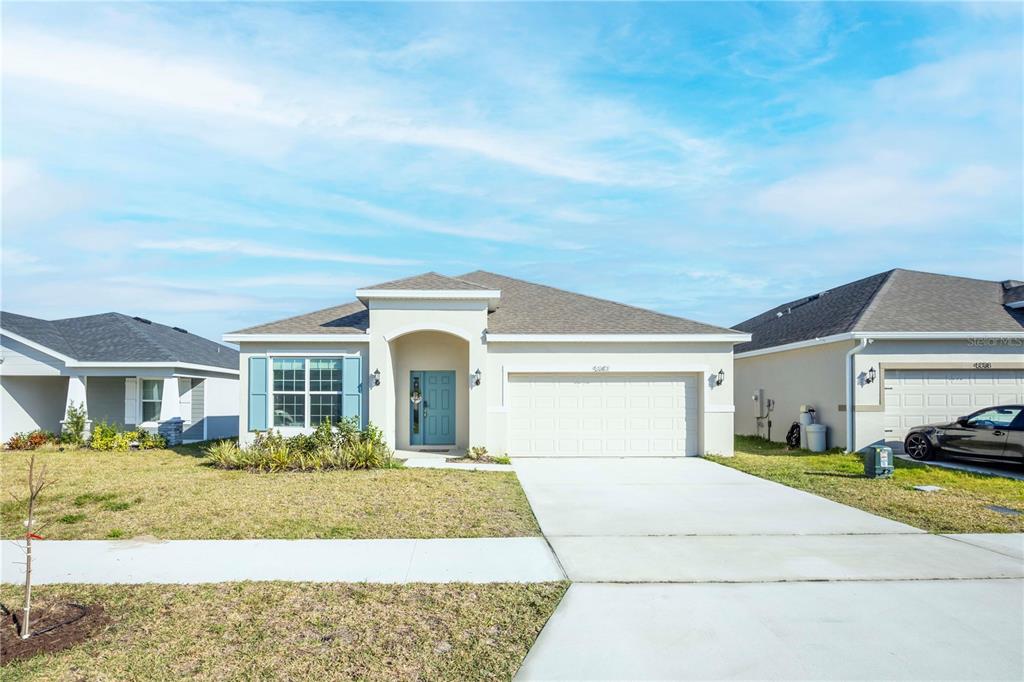 A single-story suburban house with a light-colored stucco exterior and a two-car garage — 5342 MADDIE DRIVE, HAINES CITY, FL