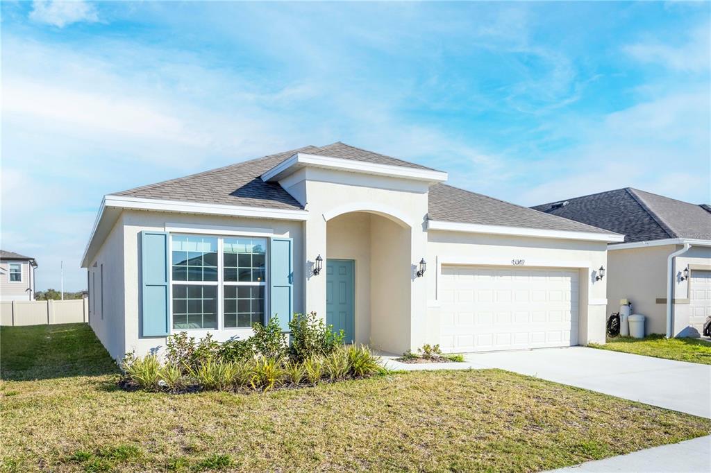 A single-story suburban house with a white stucco exterior, blue shutters, and a two-car garage — 5342 MADDIE DRIVE, HAINES CITY, FL
