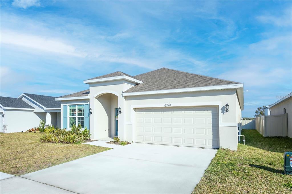 A single-story suburban house with a beige stucco exterior and a two-car garage — 5342 MADDIE DRIVE, HAINES CITY, FL