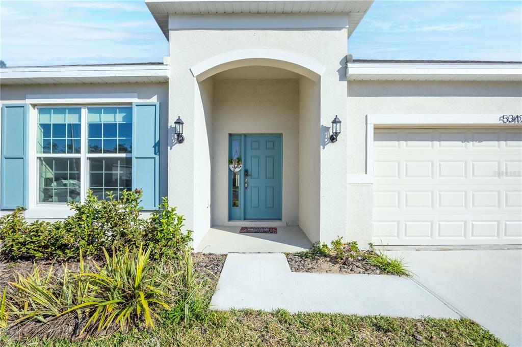 A light-colored house exterior features a blue front door, blue shutters, and a garage — 5342 MADDIE DRIVE, HAINES CITY, FL
