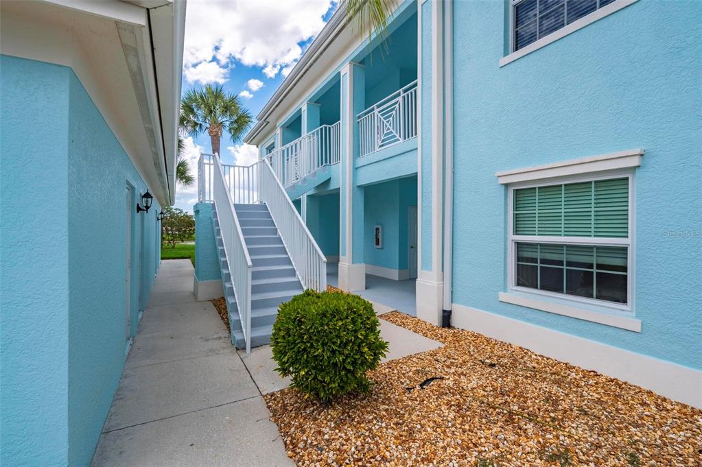 An exterior view of a blue two-story building with a staircase leading to a balcony — 5744 SABAL TRACE DRIVE UNIT 201, NORTH PORT, FL