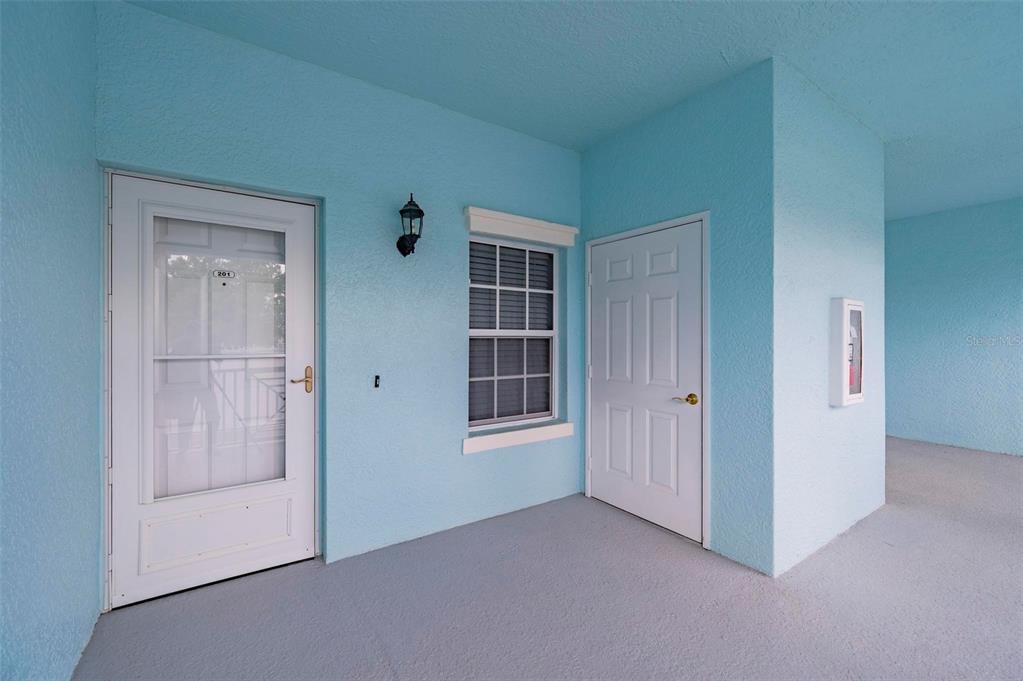 A light blue exterior entryway features a white storm door, a window, and a door — 5744 SABAL TRACE DRIVE UNIT 201, NORTH PORT, FL