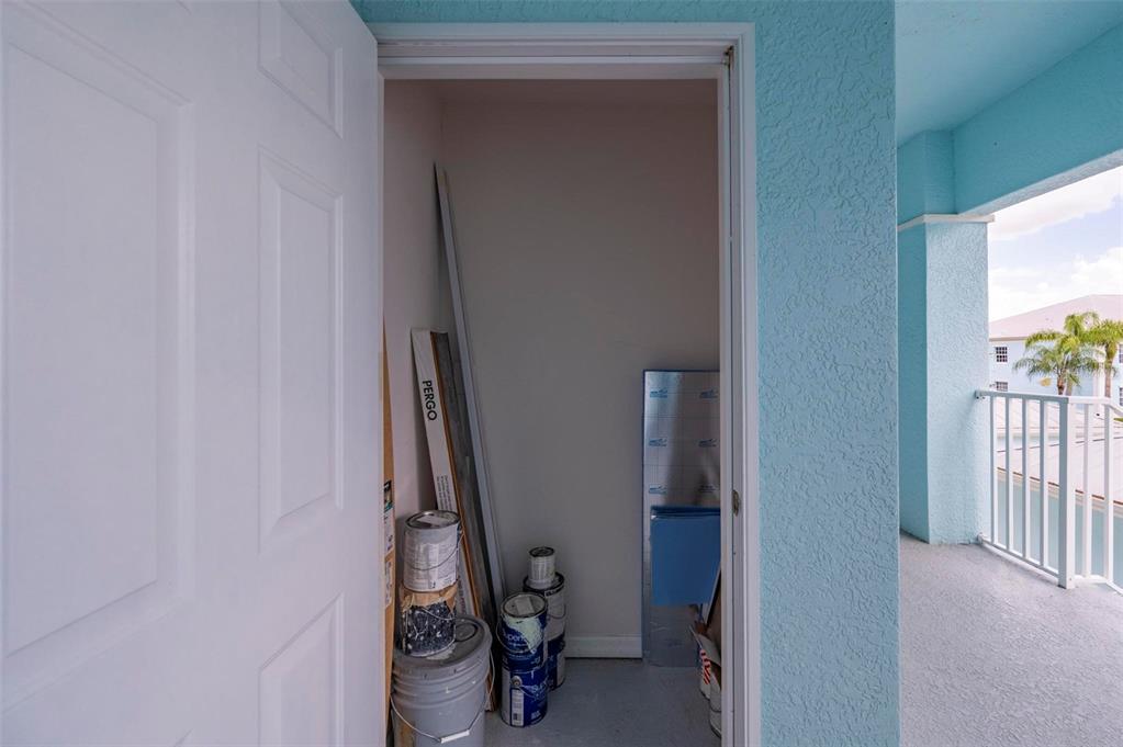 An open storage closet on a balcony contains paint cans and building materials — 5744 SABAL TRACE DRIVE UNIT 201, NORTH PORT, FL