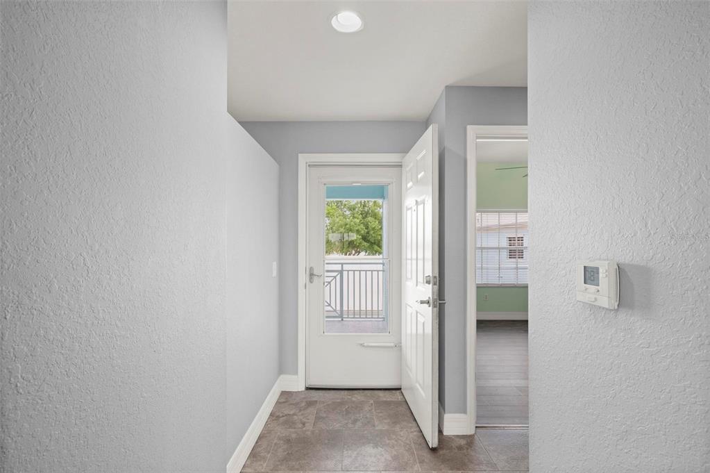 An entryway with tile flooring leads to an open door revealing a balcony — 5744 SABAL TRACE DRIVE UNIT 201, NORTH PORT, FL