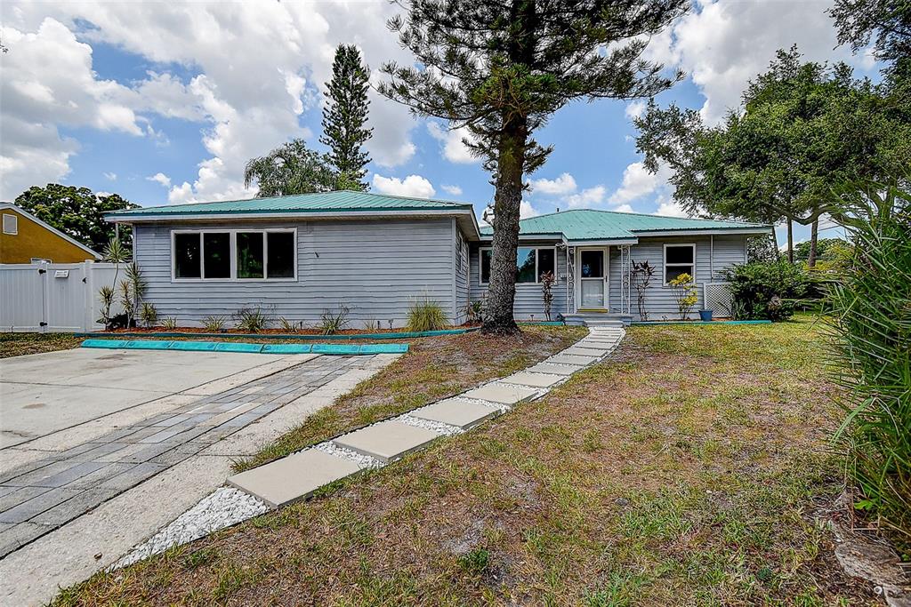 A single-story gray house with a green metal roof and a stone walkway — 1509 CANTERBURY ROAD N, ST PETERSBURG, FL