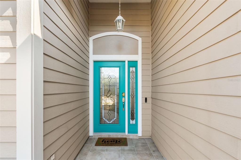 A teal front door with a glass insert and sidelight sits under a covered entryway — 3737 SW 74TH DRIVE, GAINESVILLE, FL