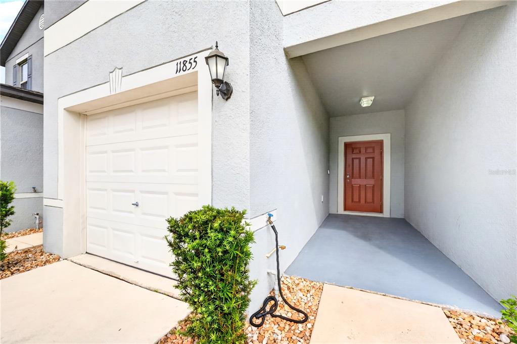 A view of a house exterior featuring a garage, a front door, and landscaping — 11855 DUMAINE VALLEY ROAD, RIVERVIEW, FL