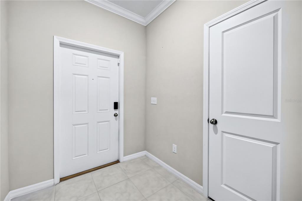 An entryway features light-colored tile flooring, neutral walls, a white front door, and a closet — 11855 DUMAINE VALLEY ROAD, RIVERVIEW, FL