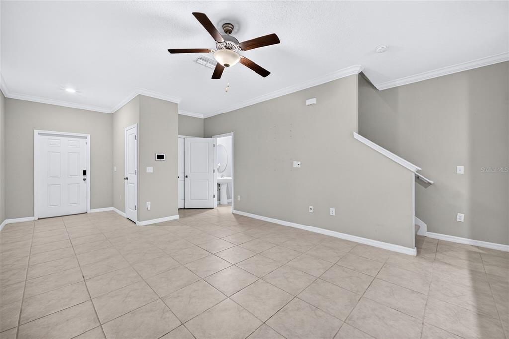 A living room with beige tile flooring, light gray walls, and a staircase — 11855 DUMAINE VALLEY ROAD, RIVERVIEW, FL
