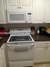 A white electric range and microwave are installed between white cabinets in a kitchen — 12142 Saint Andrews Pl # 306, Miramar FL 33025, MIRAMAR, FL
