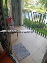 A balcony with tiled flooring, two chairs, and a metal railing overlooking a pond — 12142 Saint Andrews Pl # 306, Miramar FL 33025, MIRAMAR, FL