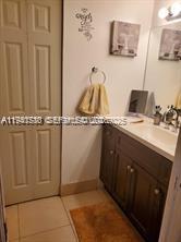 A bathroom features a dark wood vanity, a beige tiled floor, and a light-colored door — 12142 Saint Andrews Pl # 306, Miramar FL 33025, MIRAMAR, FL