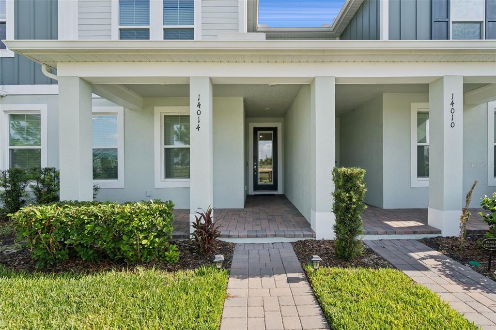 A covered entryway with a brick walkway leads to two front doors on a house — 14014 SCARLET ASTER ALLEY, WINTER GARDEN, FL