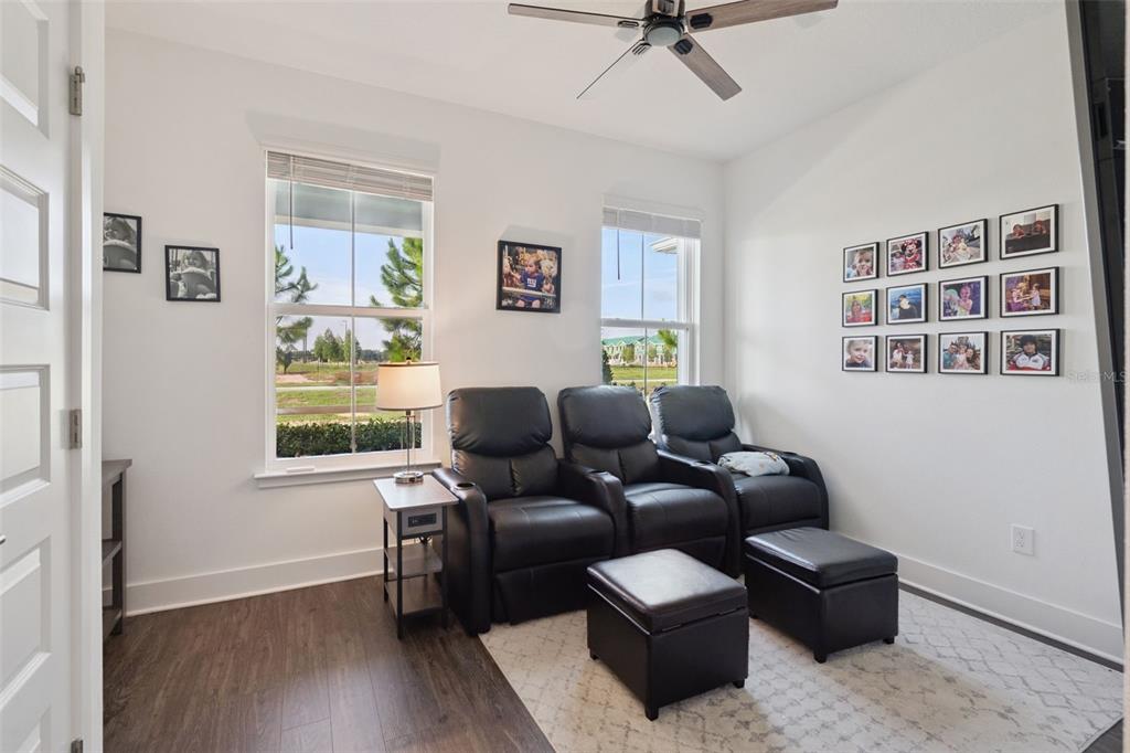 A room with dark wood flooring, three black leather recliners, and a gallery wall — 14014 SCARLET ASTER ALLEY, WINTER GARDEN, FL