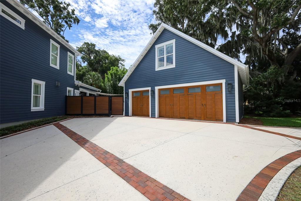 A blue-sided detached garage with wooden doors and a concrete driveway with brick accents — 20 W CREST AVENUE, WINTER GARDEN, FL