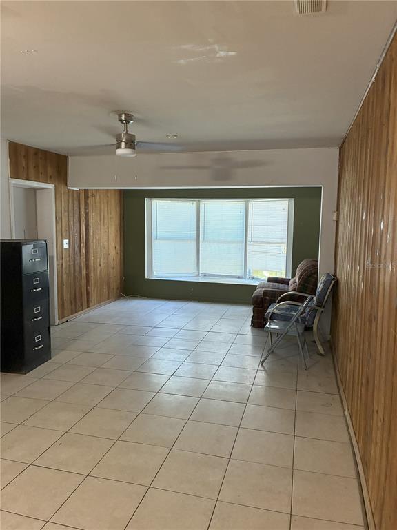 A room with light tile flooring, wood-paneled walls, and a large bay window — 3016 BLOOMINGDALE AVENUE, VALRICO, FL