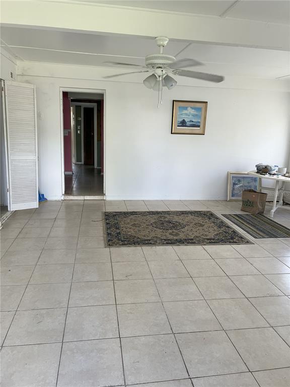 A room with white walls, tiled floors, a ceiling fan, and a doorway leading inside — 3016 BLOOMINGDALE AVENUE, VALRICO, FL