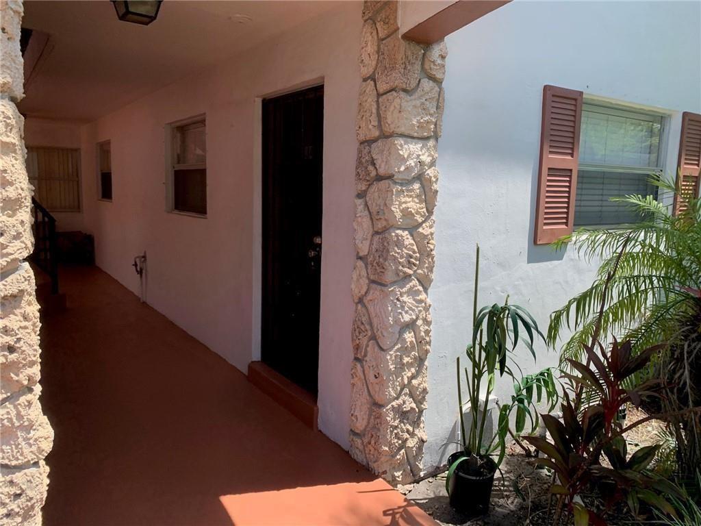 A covered walkway leads to a dark front door beside a stone-accented exterior wall — 206 SW 1st Street # 4, Pompano Beach FL 33060, POMPANO BEACH, FL