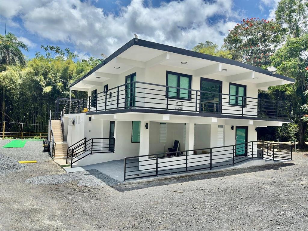 A two-story white house with black trim, metal railings, and an outdoor staircase — Solar 2 BARRIO ZARZAL, RIO GRANDE, PR