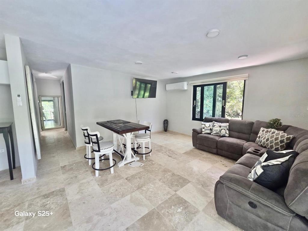 A living room features a sectional sofa, a dining table with chairs, and tile flooring — Solar 2 BARRIO ZARZAL, RIO GRANDE, PR