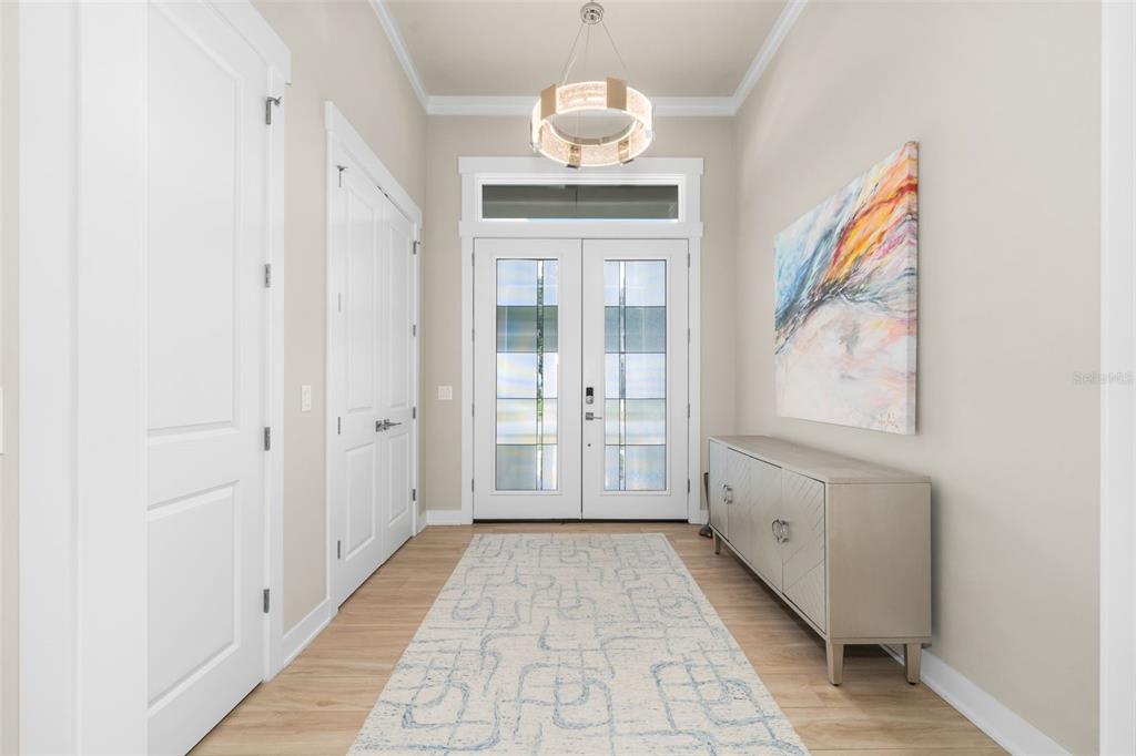 A bright entryway features a double front door, a patterned rug, and a modern chandelier — 828 SW 131ST STREET, NEWBERRY, FL