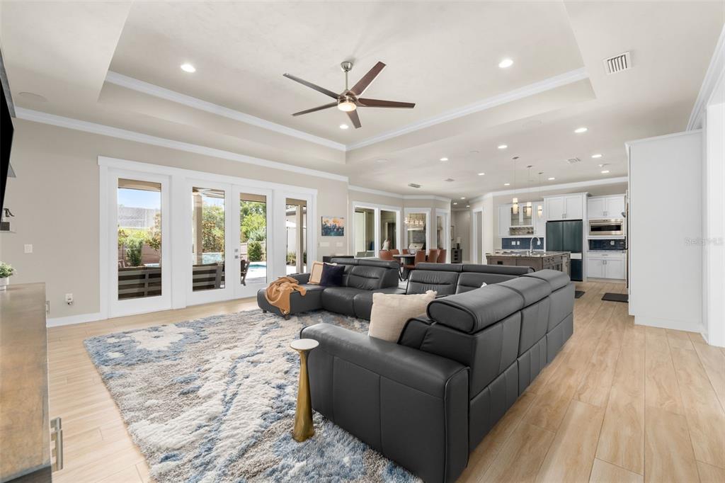 A spacious open-concept living room features a large black sectional, area rug, and kitchen beyond — 828 SW 131ST STREET, NEWBERRY, FL