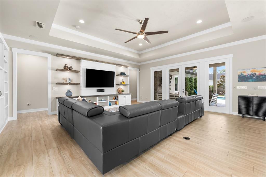A living room features a gray sectional sofa, a tray ceiling, and a built-in media center — 828 SW 131ST STREET, NEWBERRY, FL