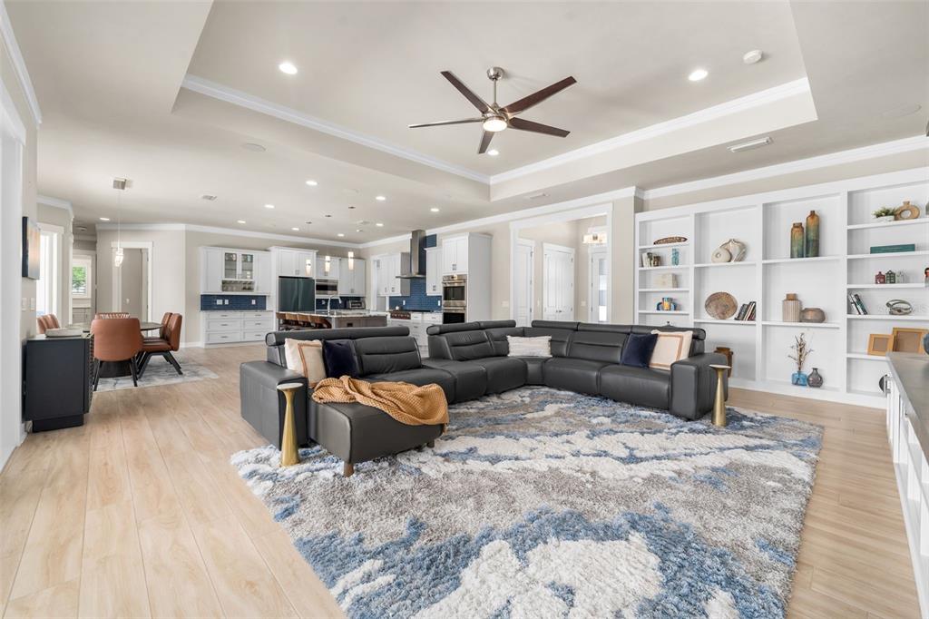 A spacious open-concept living room features a large gray sectional, built-in shelving, and light flooring — 828 SW 131ST STREET, NEWBERRY, FL