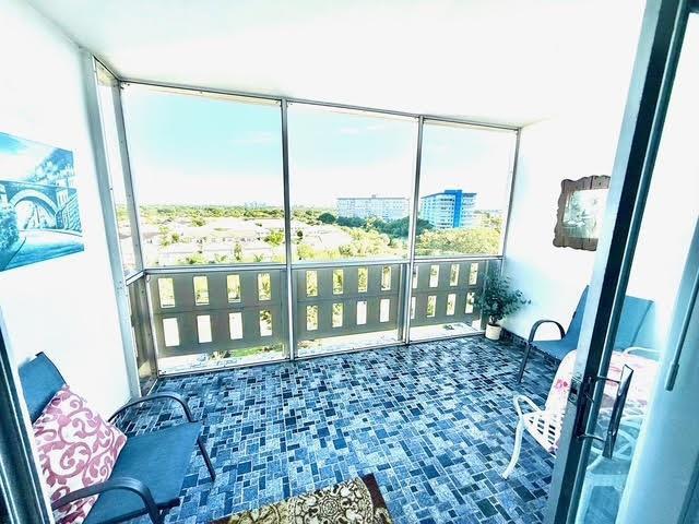 A sunroom with blue tiled flooring, large windows, and outdoor furniture overlooking a suburban landscape — 4330 Hillcrest Drive # 904, Hollywood FL 33021, HOLLYWOOD, FL