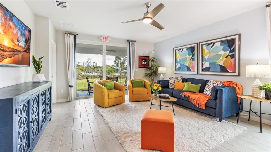 A living room features a blue sofa, two yellow armchairs, and a sliding glass door — 4727 SCHUBERT TRAIL, NORTH PORT, FL