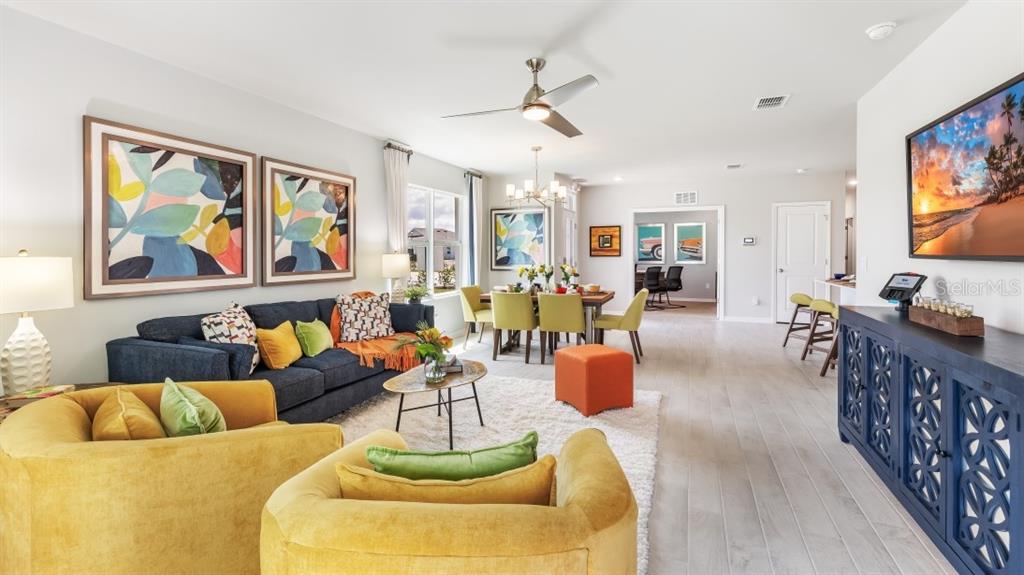A living room features a blue sofa, yellow armchairs, a dining area, and light flooring — 4727 SCHUBERT TRAIL, NORTH PORT, FL