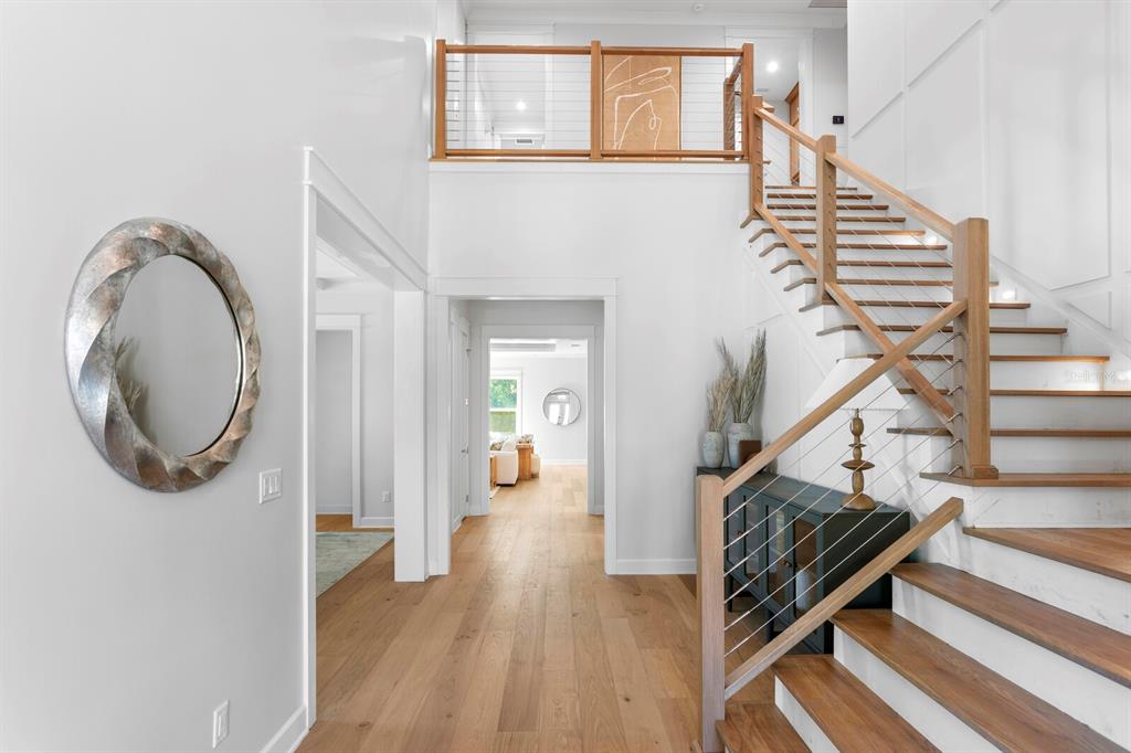 A bright foyer features light wood flooring, a staircase with cable railings, and white walls — 2312 S OCCIDENT STREET, TAMPA, FL