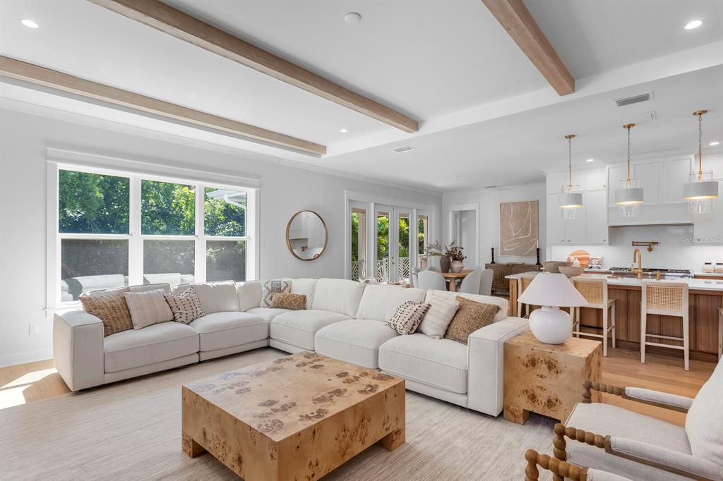 A bright living room features a large sectional sofa, wooden coffee table, and exposed ceiling beams — 2312 S OCCIDENT STREET, TAMPA, FL
