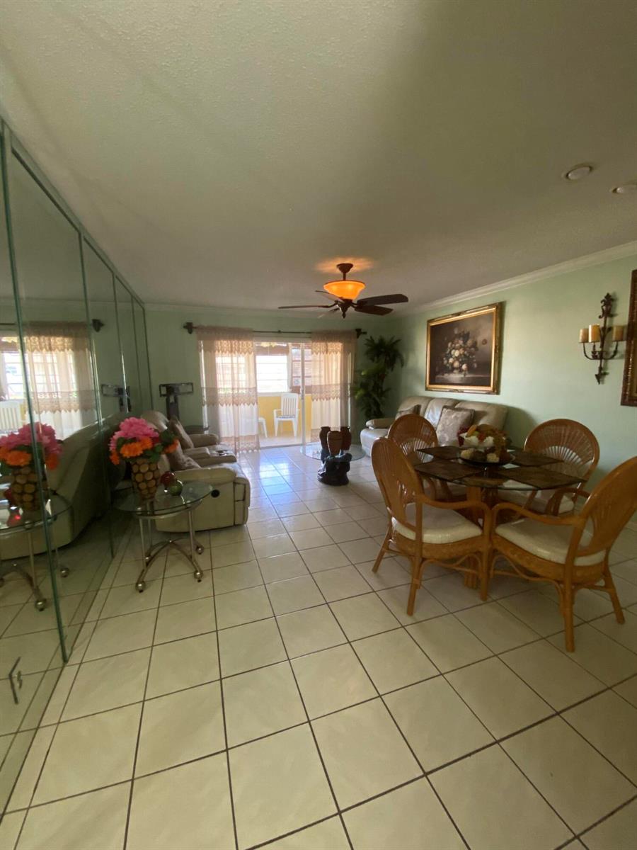A living and dining area with tiled floors, a ceiling fan, and a balcony view — 715 Lori Drive # 302, Palm Springs FL 33461, PALM SPRINGS, FL