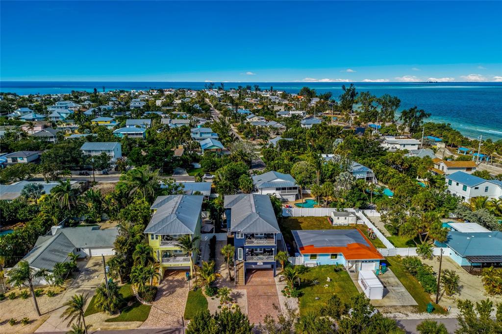 An aerial view shows several coastal homes with metal roofs surrounded by lush tropical vegetation — 159 CRESCENT DRIVE, ANNA MARIA, FL