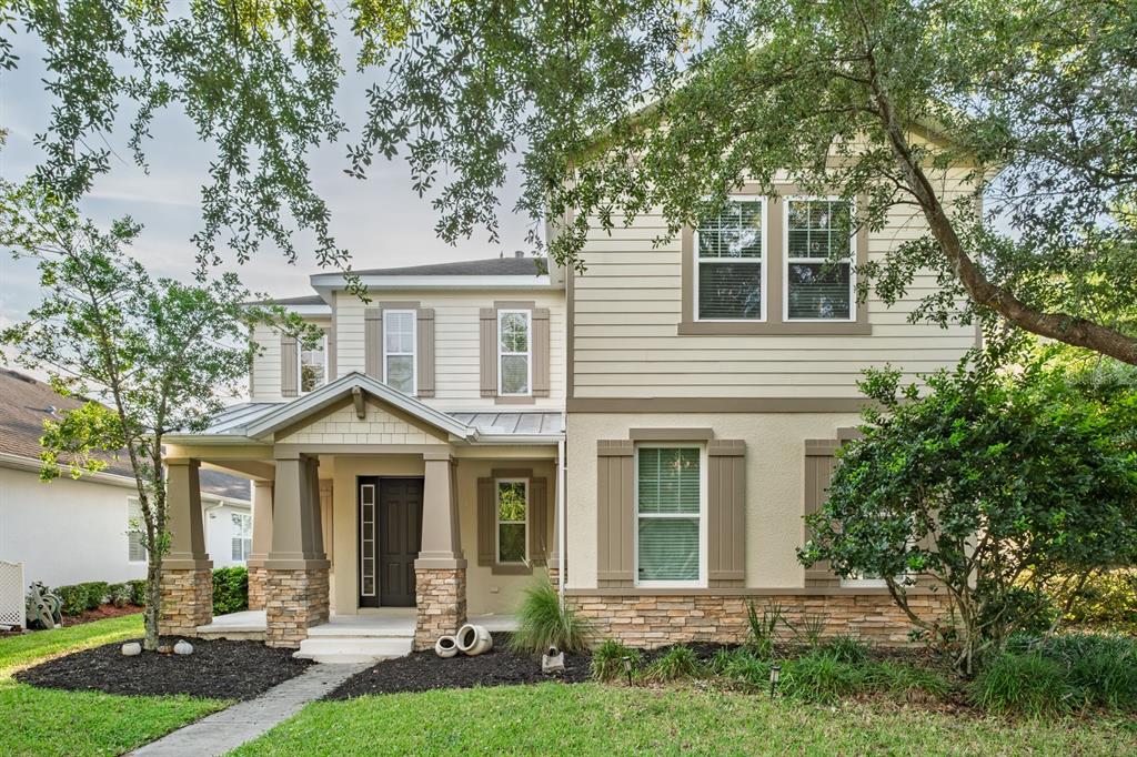 A two-story house features a stone-based porch, tan siding, and brown shutters — 7912 HAMPTON LAKE DRIVE, TAMPA, FL