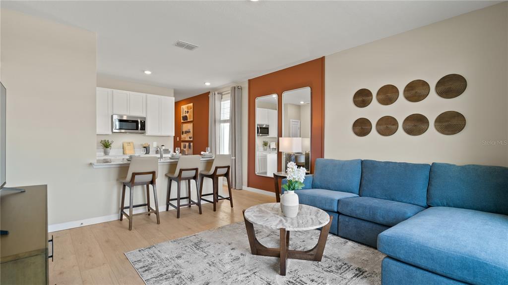 A living room with a blue sectional sofa, marble coffee table, and an adjacent kitchen — 5247 HAVEN VIEW DRIVE, CLERMONT, FL