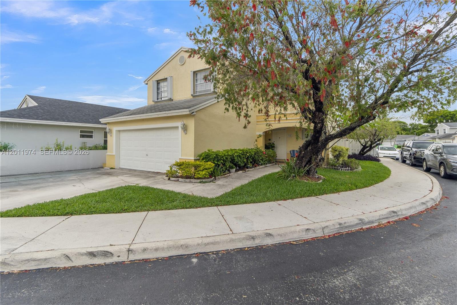 A two-story yellow house with a garage and a large tree in the front yard — 375 W Riverbend Dr, Sunrise FL 33326, SUNRISE, FL