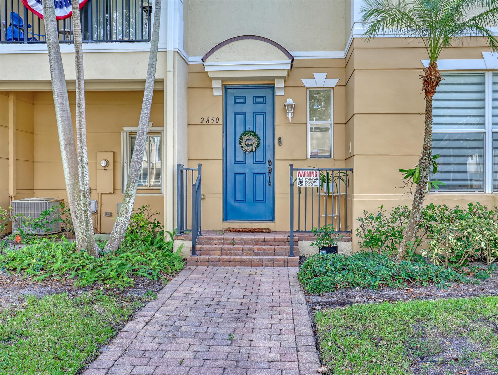 A blue front door with a wreath is centered on a tan building exterior — 2850 S Oasis Drive, Boynton Beach FL 33426, BOYNTON BEACH, FL