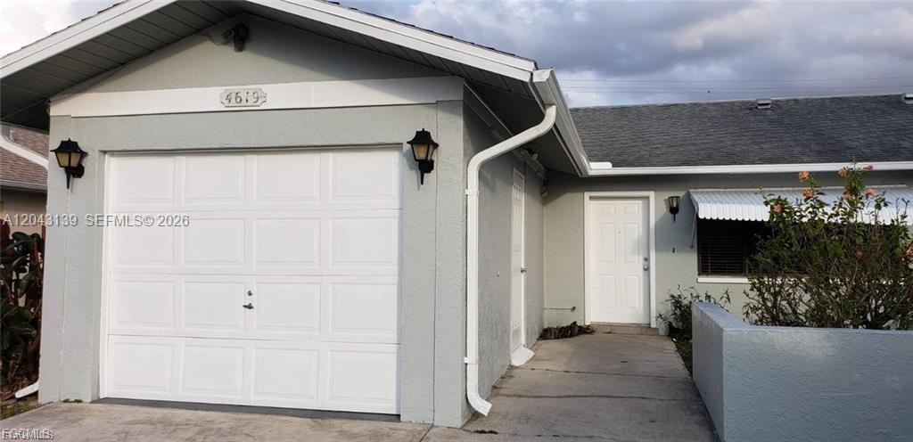 The exterior of a light-colored house features a single-car garage and a front entrance — 4619 SW 7TH PL, Cape Coral FL 33914, CAPE CORAL, FL