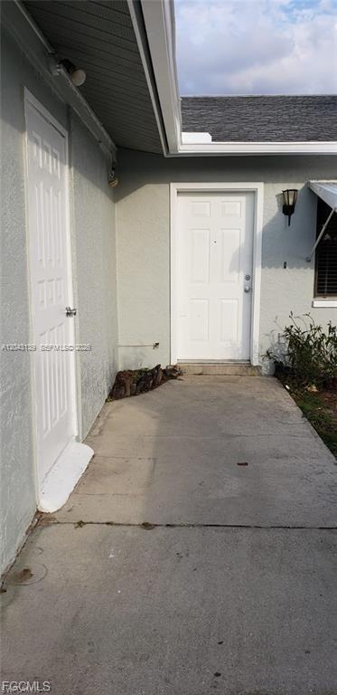 A concrete walkway leads to two white exterior doors on the side of a house — 4619 SW 7TH PL, Cape Coral FL 33914, CAPE CORAL, FL