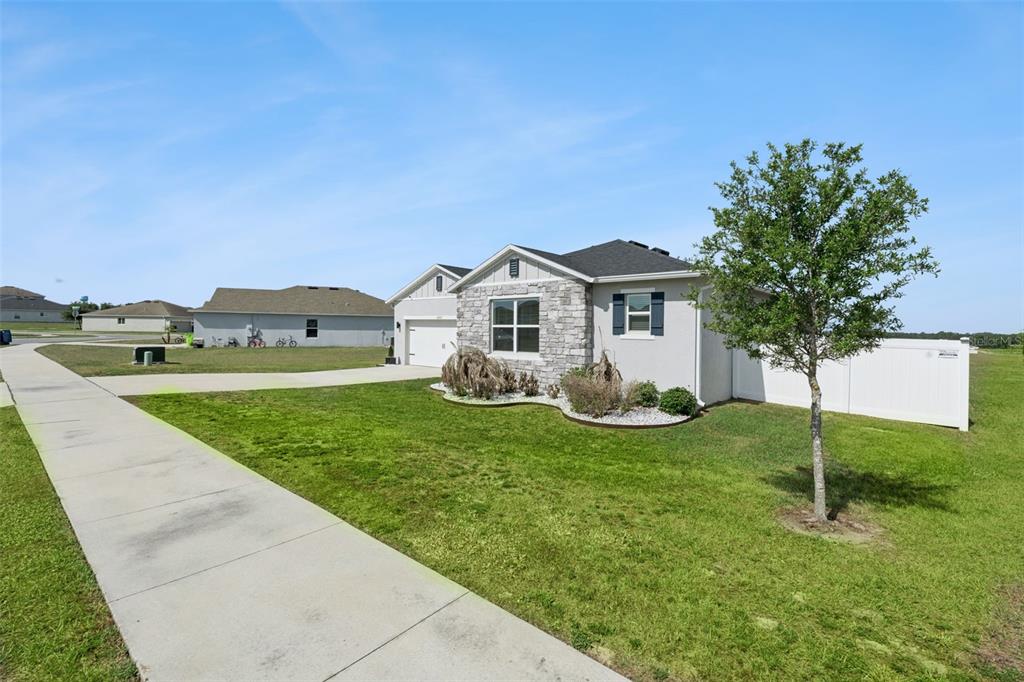 A single-story house with a stone facade, a white fence, and a concrete driveway — 2429 BEGONIA STREET, MASCOTTE, FL