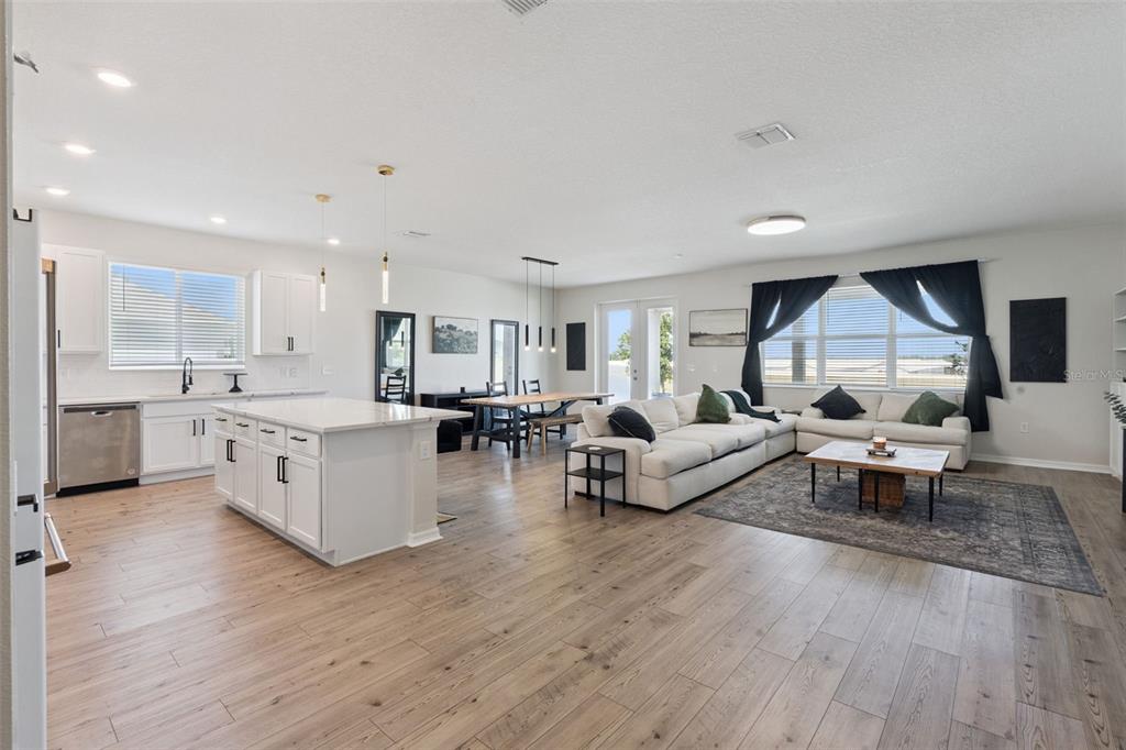 An open-concept kitchen and living area with white cabinetry, a large island, and wood flooring — 2429 BEGONIA STREET, MASCOTTE, FL