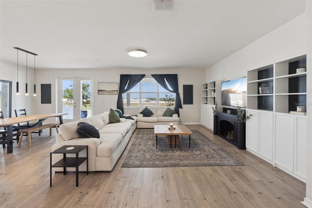 A bright living room features a large sectional sofa, a wooden coffee table, and built-in shelving — 2429 BEGONIA STREET, MASCOTTE, FL