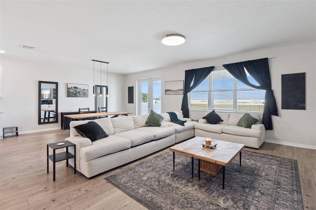 A living room with a large white sectional, wooden coffee table, and dining area — 2429 BEGONIA STREET, MASCOTTE, FL